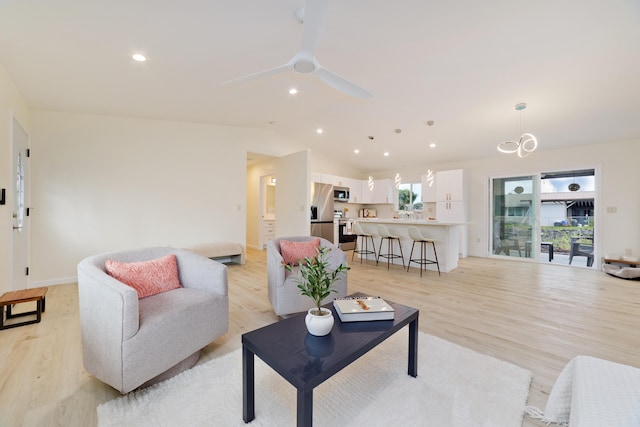 living room featuring light hardwood / wood-style floors, vaulted ceiling, and ceiling fan