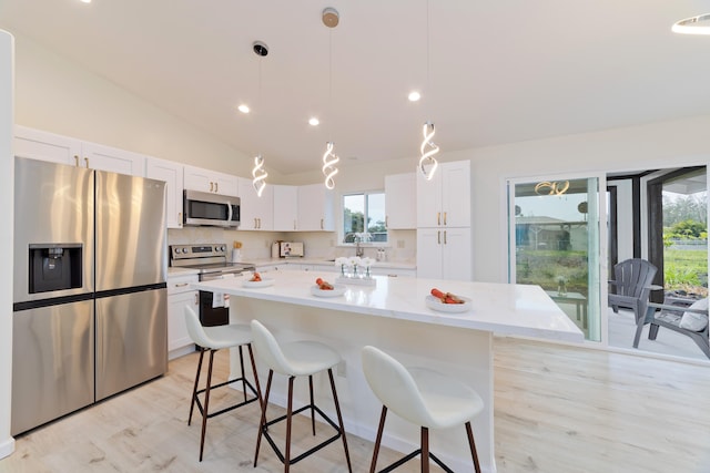 kitchen featuring a center island, stainless steel appliances, lofted ceiling, decorative light fixtures, and white cabinets