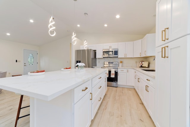 kitchen featuring pendant lighting, light wood-type flooring, a kitchen island, white cabinetry, and stainless steel appliances