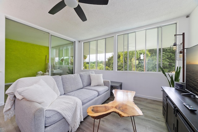 living room featuring ceiling fan, a textured ceiling, and light hardwood / wood-style floors