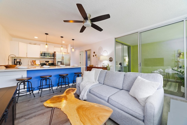 living room with a textured ceiling, light hardwood / wood-style flooring, and ceiling fan