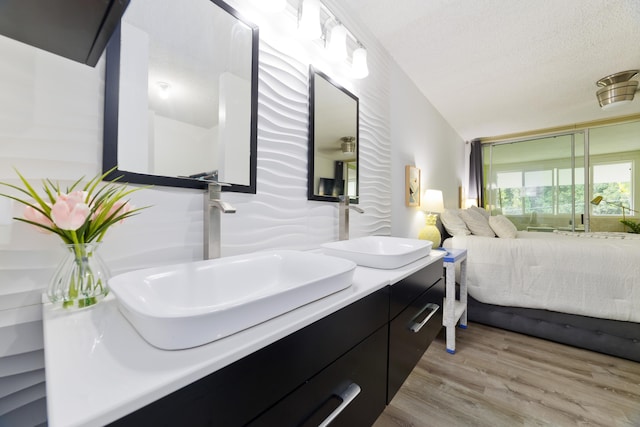 bathroom with hardwood / wood-style flooring, vanity, lofted ceiling, and a textured ceiling