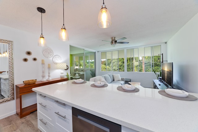 kitchen with hanging light fixtures, dishwasher, white cabinets, and light wood-type flooring