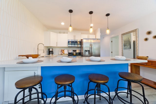 kitchen featuring sink, hanging light fixtures, stainless steel appliances, white cabinets, and decorative backsplash