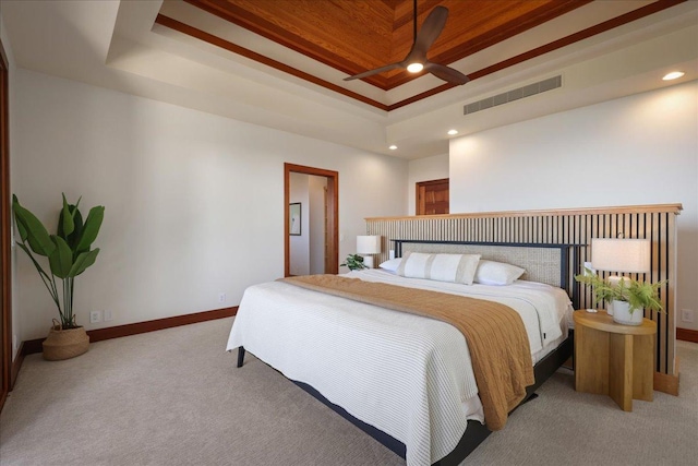 bedroom with ceiling fan, a tray ceiling, crown molding, and light carpet