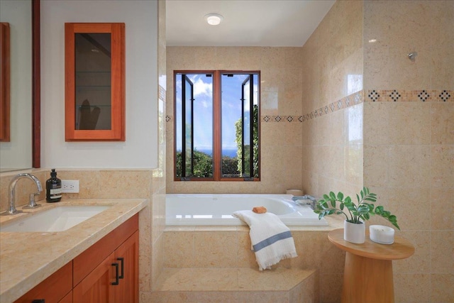 bathroom featuring vanity, tiled tub, and tile walls