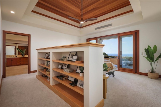 interior space featuring ensuite bathroom, access to exterior, and a tray ceiling