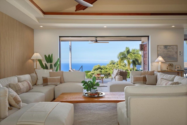 living room with wood walls, ceiling fan, a healthy amount of sunlight, and a water view