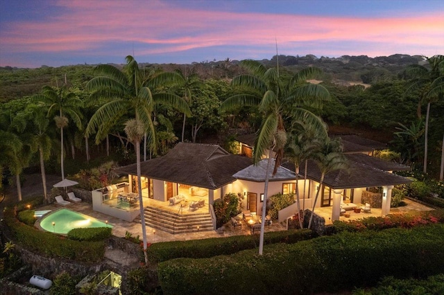 back house at dusk featuring a patio area