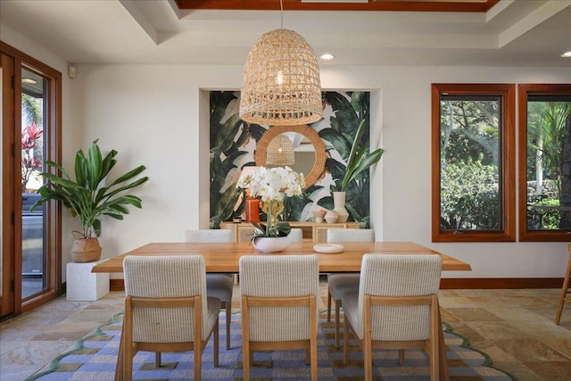 dining area featuring a raised ceiling, a wealth of natural light, and a notable chandelier