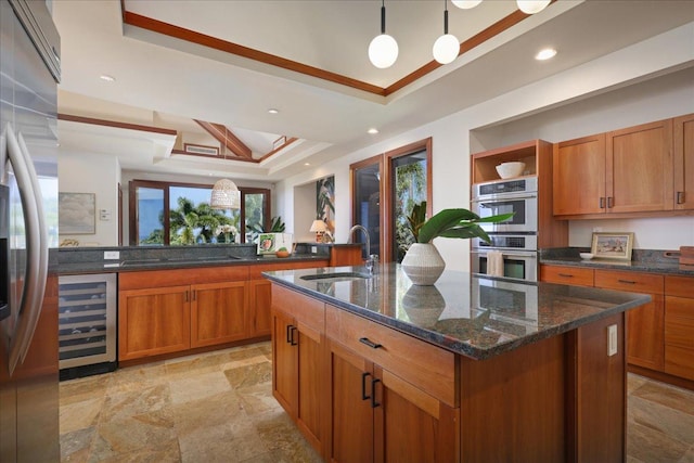 kitchen featuring a kitchen island with sink, wine cooler, a tray ceiling, appliances with stainless steel finishes, and sink