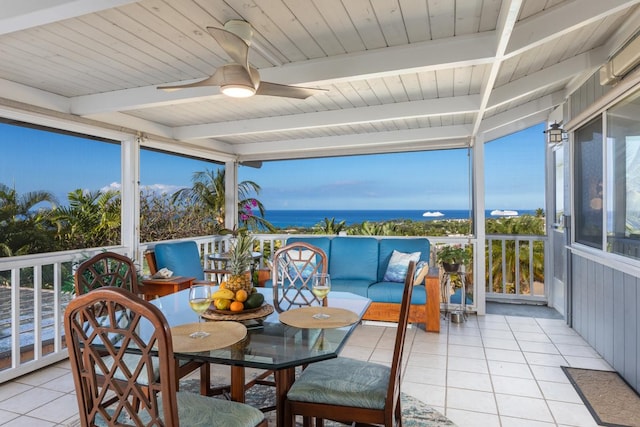 sunroom / solarium featuring ceiling fan, beamed ceiling, and a water view