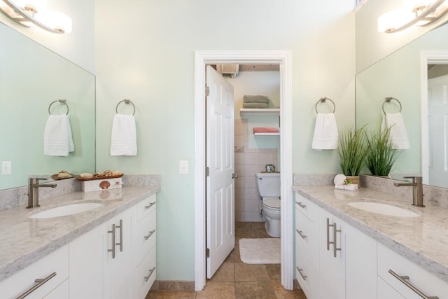 bathroom with toilet, vanity, tile patterned flooring, and tile walls