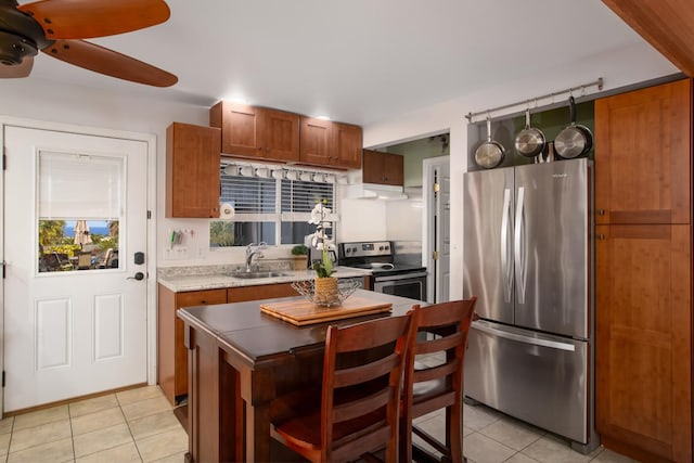 kitchen with a kitchen island, stainless steel appliances, sink, light tile patterned flooring, and ceiling fan