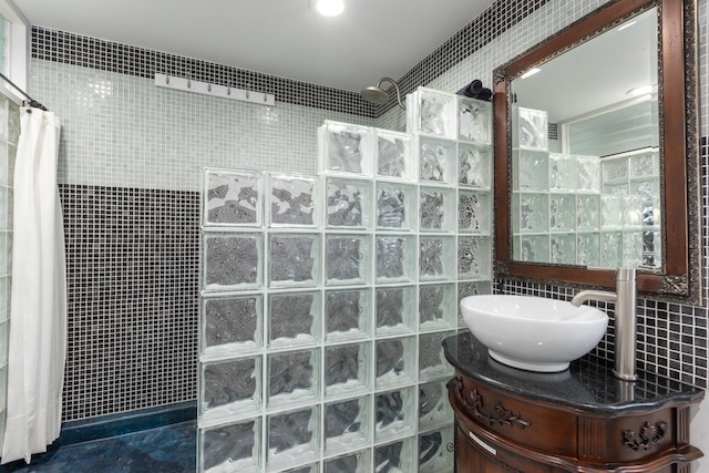 bathroom with tile walls, tiled shower, and vanity