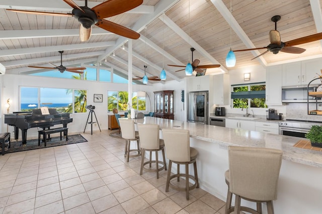 kitchen with a kitchen breakfast bar, appliances with stainless steel finishes, white cabinetry, and light stone counters