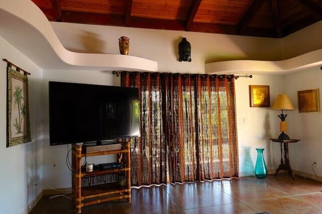 living room with beam ceiling, a high ceiling, and wooden ceiling