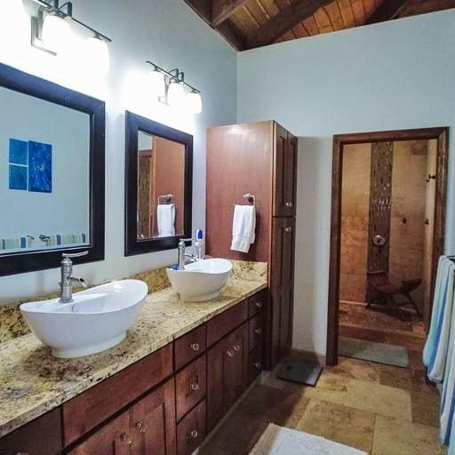 bathroom featuring a shower, vanity, lofted ceiling with beams, and wood ceiling