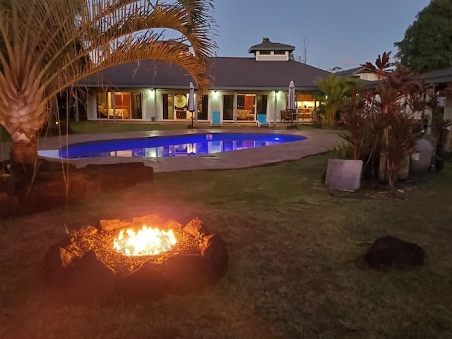 pool at dusk featuring a patio area and an outdoor fire pit