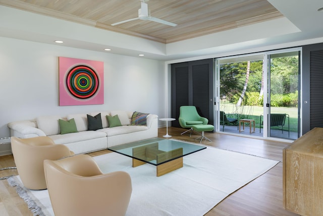 living room featuring crown molding, wood ceiling, a tray ceiling, and light hardwood / wood-style flooring