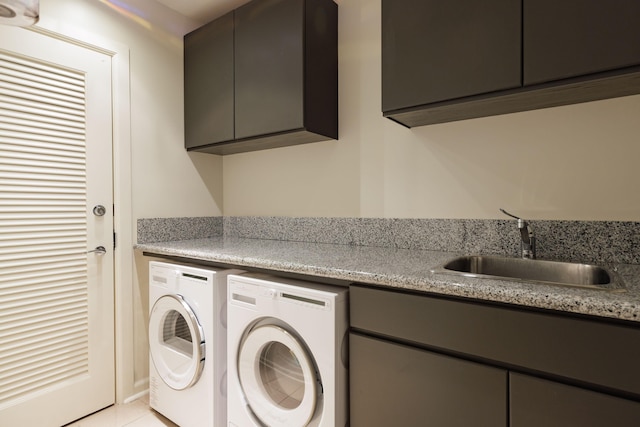 clothes washing area with cabinets, sink, light tile patterned floors, and washer and clothes dryer