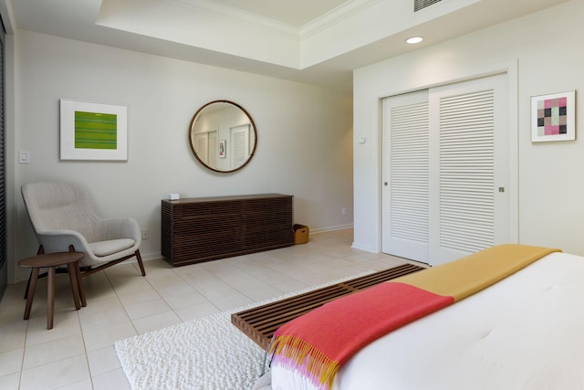 tiled bedroom with a raised ceiling, crown molding, and a closet