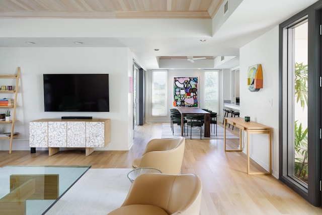 living room with crown molding, wood ceiling, light hardwood / wood-style floors, and a tray ceiling