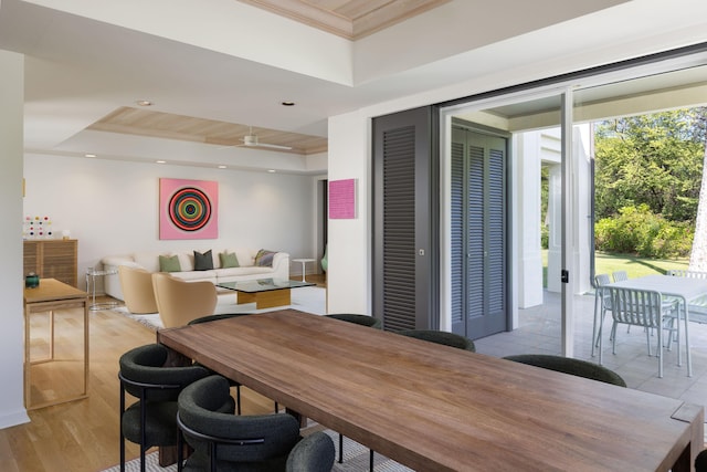 dining area featuring crown molding, a tray ceiling, ceiling fan, and light wood-type flooring