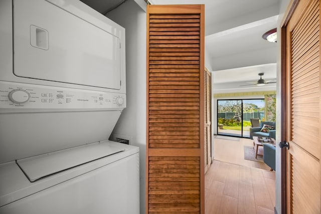 clothes washing area with stacked washer / dryer, ceiling fan, and light wood-type flooring