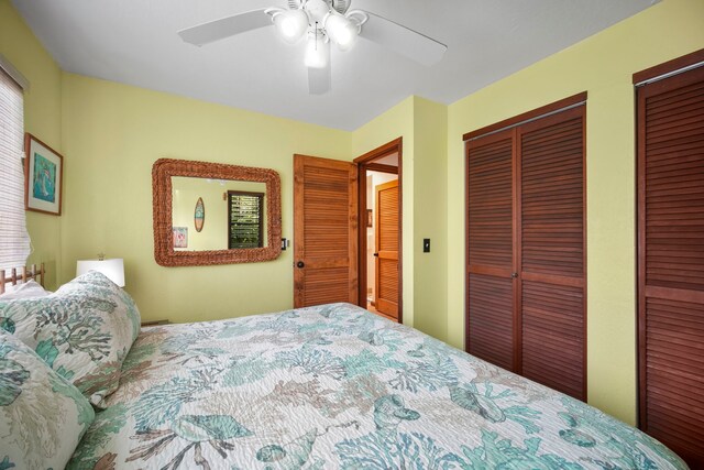 bedroom with ceiling fan and two closets