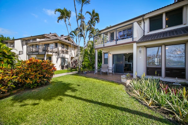 rear view of property with a balcony, a yard, and a patio