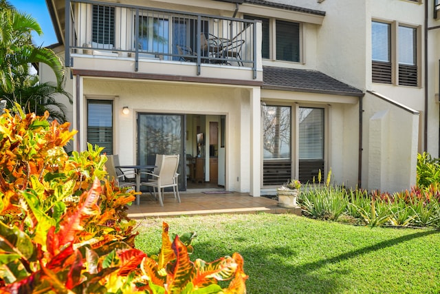 back of property with a balcony, a yard, and a patio area