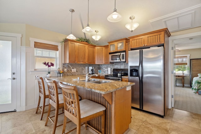 kitchen with appliances with stainless steel finishes, decorative light fixtures, kitchen peninsula, and light stone countertops