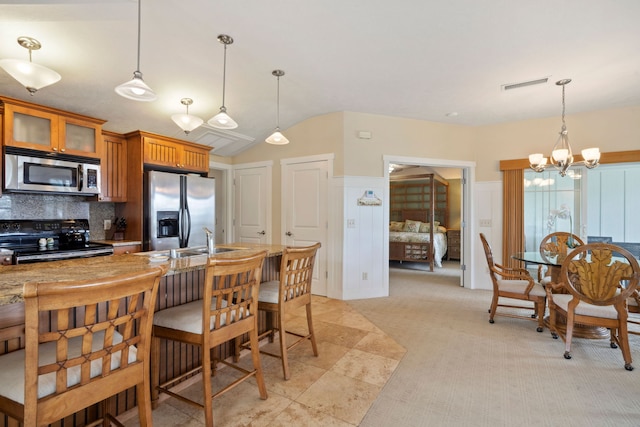 kitchen featuring hanging light fixtures, lofted ceiling, appliances with stainless steel finishes, and backsplash