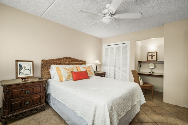 bedroom featuring a closet, ceiling fan, light tile patterned floors, and a textured ceiling