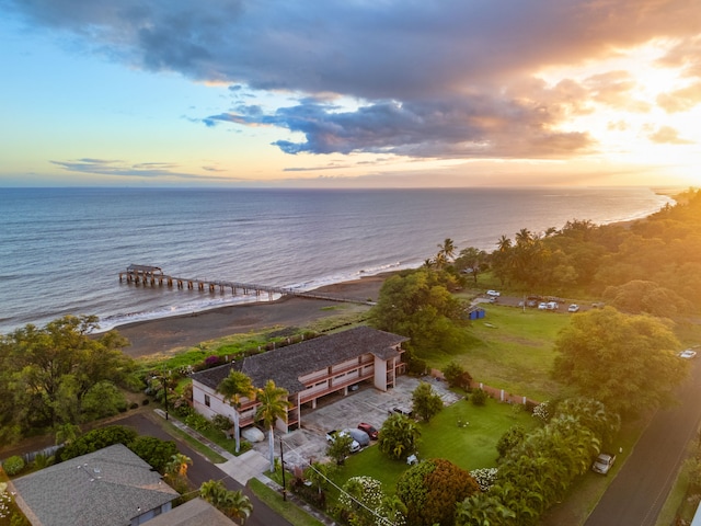 aerial view at dusk featuring a water view and a view of the beach