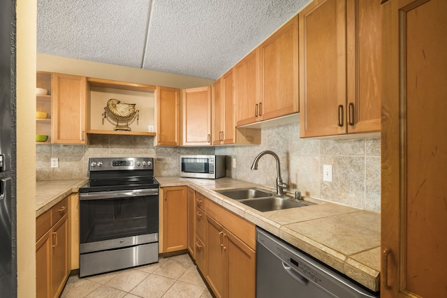 kitchen featuring appliances with stainless steel finishes, sink, backsplash, light tile patterned flooring, and a textured ceiling