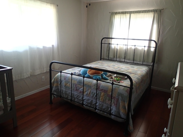 bedroom featuring multiple windows and dark hardwood / wood-style floors