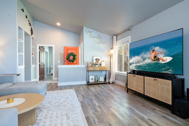 living room with vaulted ceiling, built in features, and hardwood / wood-style flooring