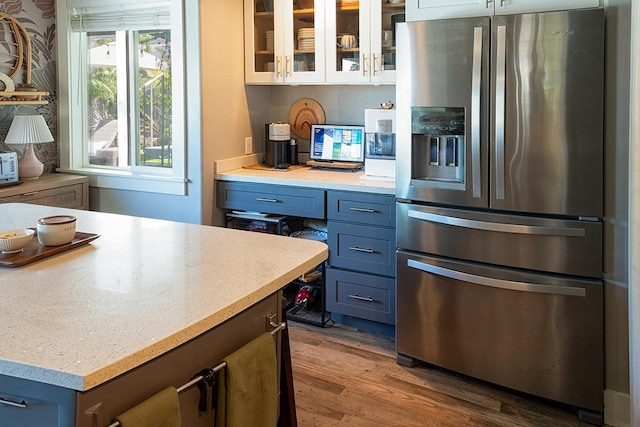 kitchen featuring stainless steel fridge with ice dispenser, white cabinetry, blue cabinets, and light wood-type flooring