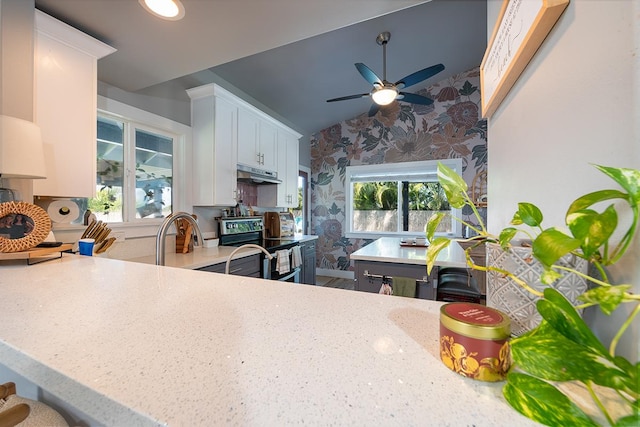 kitchen featuring ceiling fan, stainless steel electric stove, light stone countertops, vaulted ceiling, and white cabinets