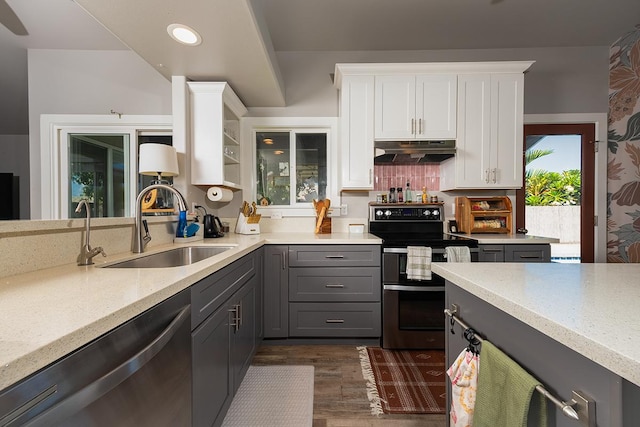 kitchen featuring tasteful backsplash, dishwashing machine, double oven range, sink, and white cabinets