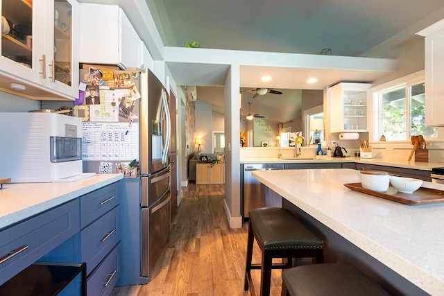 kitchen with sink, white cabinetry, light hardwood / wood-style flooring, appliances with stainless steel finishes, and blue cabinetry