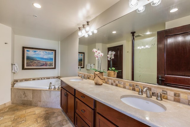 bathroom with vanity, tiled tub, and decorative backsplash