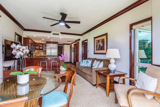 carpeted living room with crown molding and ceiling fan