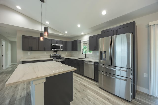 kitchen with lofted ceiling, a center island, pendant lighting, appliances with stainless steel finishes, and light stone counters