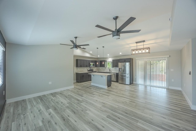 kitchen featuring pendant lighting, appliances with stainless steel finishes, a center island, lofted ceiling, and light wood-type flooring