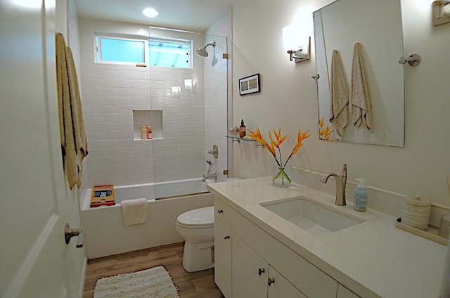 full bathroom with hardwood / wood-style floors, toilet, vanity, and tiled shower / bath