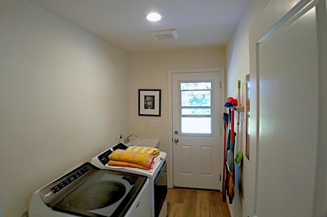 washroom featuring sink, washing machine and dryer, and light wood-type flooring