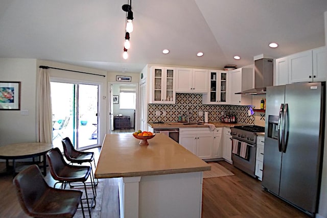 kitchen featuring appliances with stainless steel finishes, dark wood-type flooring, wall chimney range hood, white cabinets, and a center island